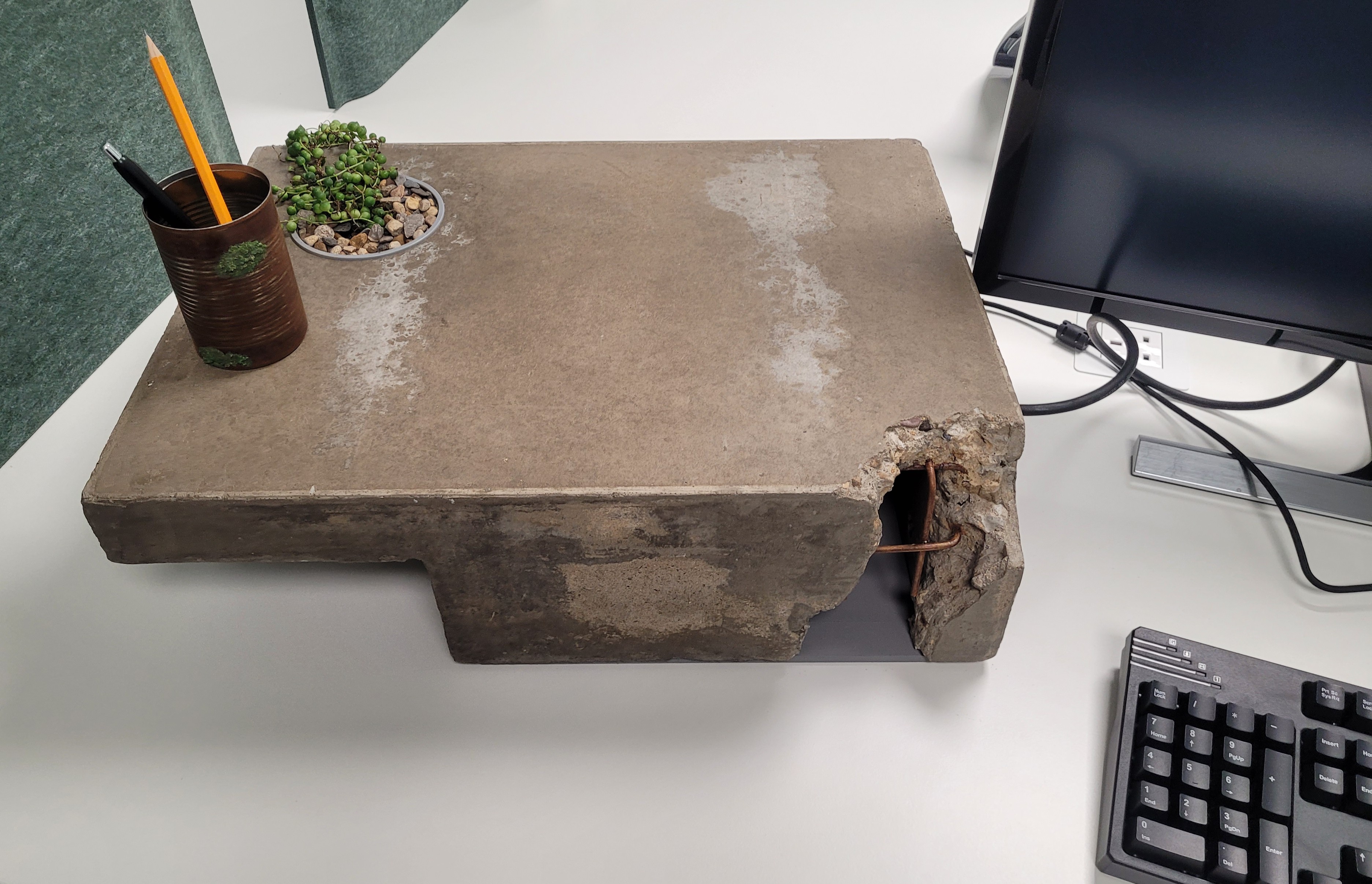 A concrete laptop stand, in brutalist architectural style, with a deliberately dilapidated corner